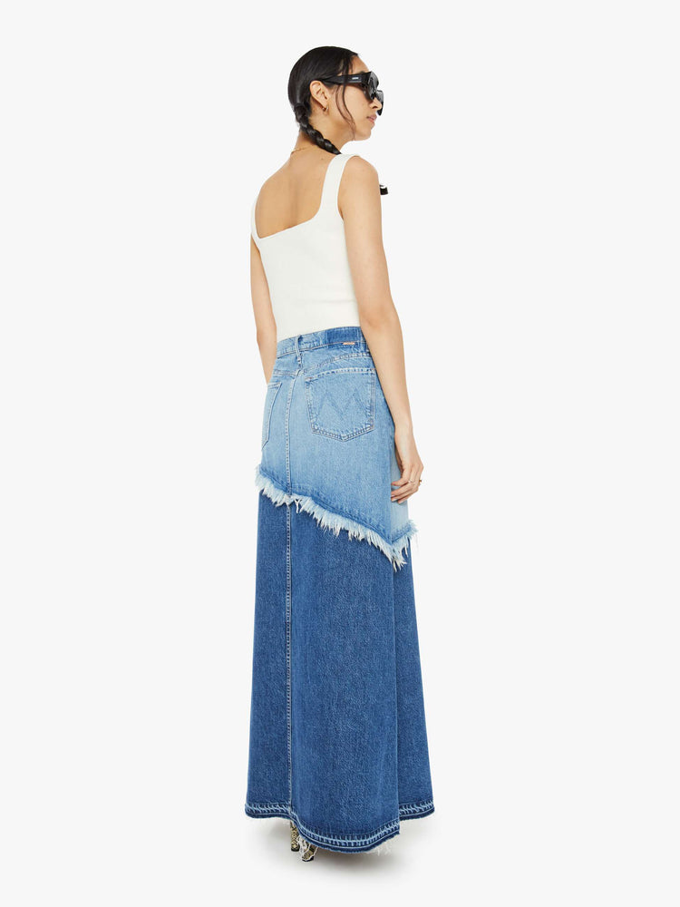 Back view of a woman in denim maxi skirt with a button fly, frayed hem and relaxed fit that's designed to sit on the hips in half light blue and half mid blue.