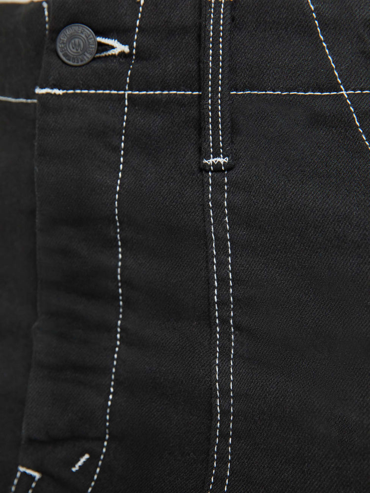 Close up view of a woman in a black high-waisted mini skirt with a button fly, oversized patch pockets and a hem that hits mid-thigh.