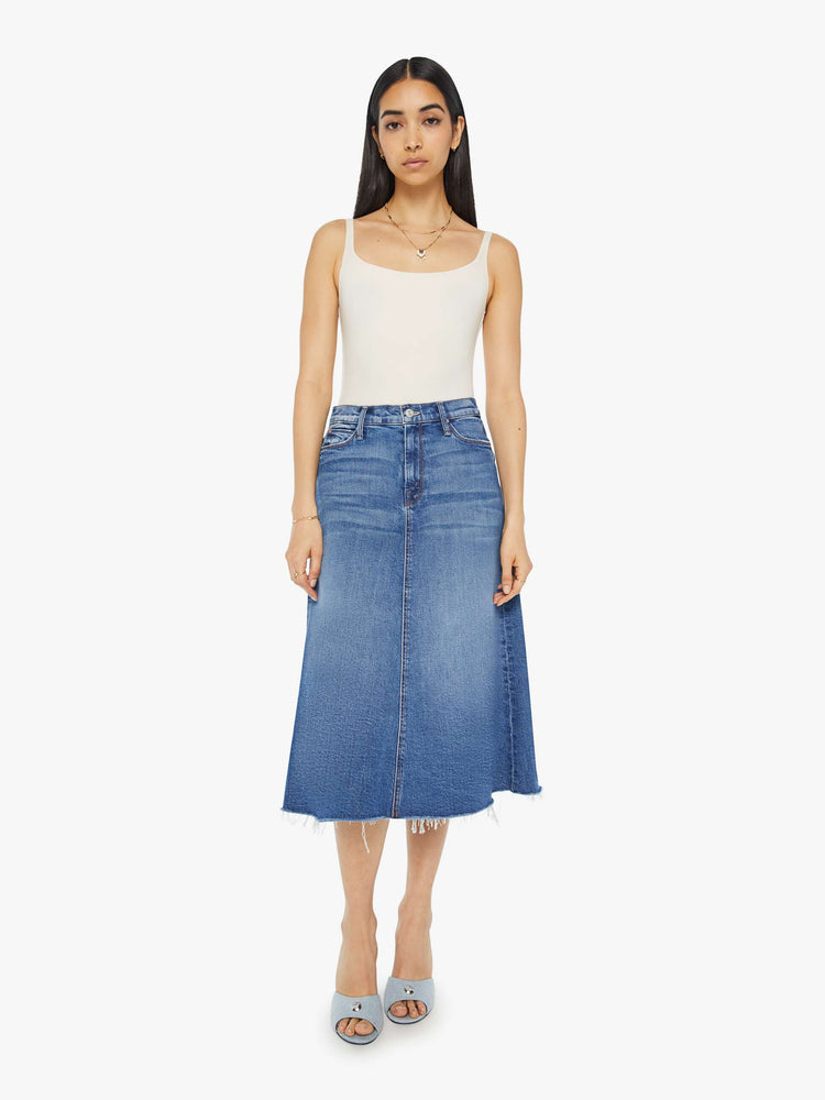 Front view of a woman high waisted midi skirt with an A-line fit and a frayed hem in medium blue wash.