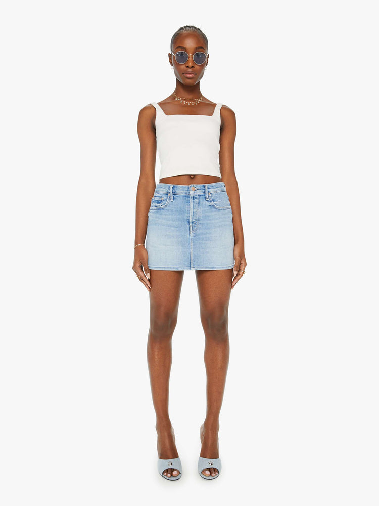 Front view of a woman denim mini skirt  designed to be worn lower on the hips with a button fly, slim fit and thigh-grazing hem in a light blue wash.