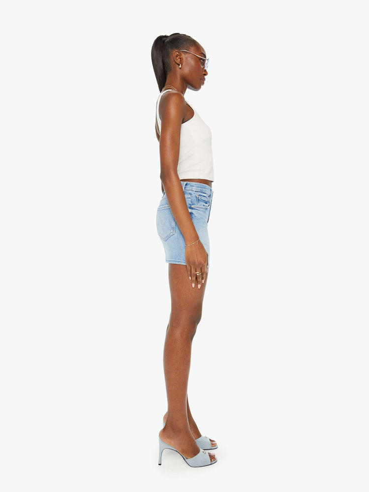 Side view of a woman denim mini skirt designed to be worn lower on the hips with a button fly, slim fit and thigh-grazing hem in a light blue wash.