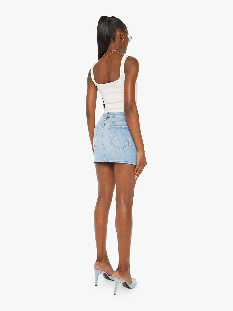 Back view of a woman denim mini skirt designed to be worn lower on the hips with a button fly, slim fit and thigh-grazing hem in a light blue wash.