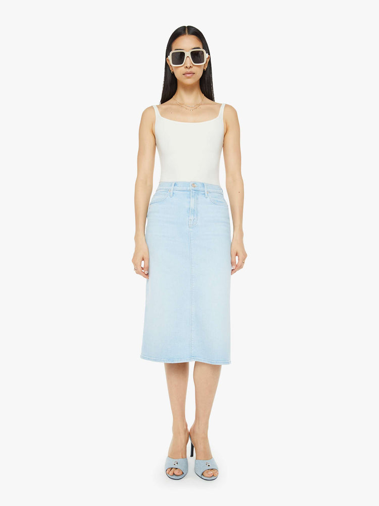 Front view of woman in a high-waisted denim midi skirt with an A-line fit and a calf-length hem in a light blue wash.