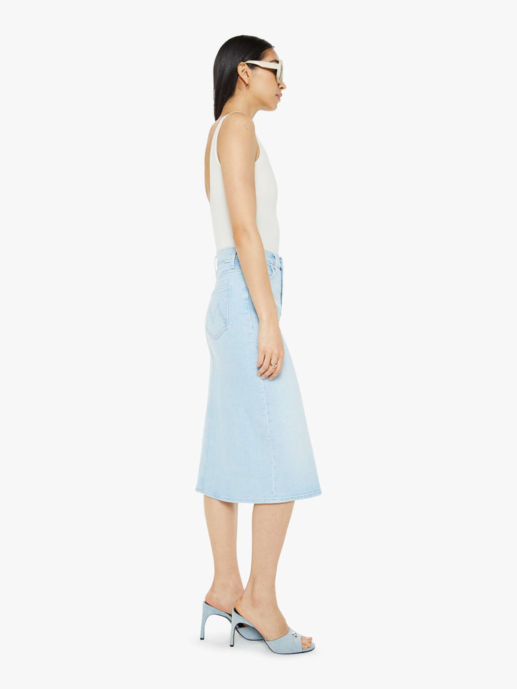 Side view of woman in a high-waisted denim midi skirt with an A-line fit and a calf-length hem in a light blue wash.