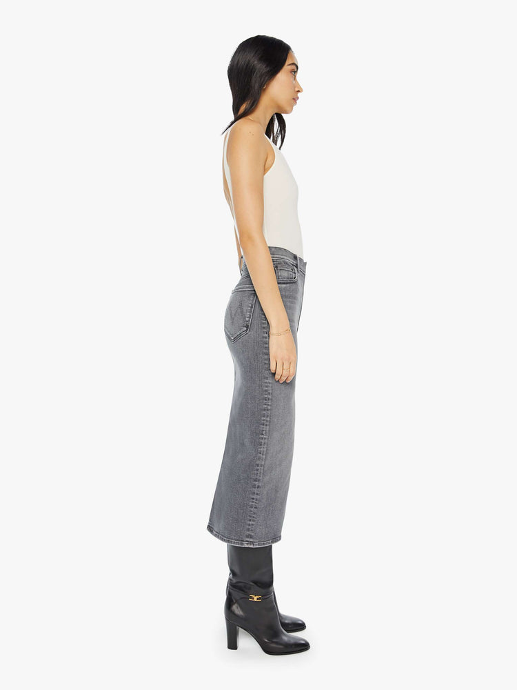 Side view of a grey denim pencil skirt with a high rise, narrow fit and a thigh-high front slit.