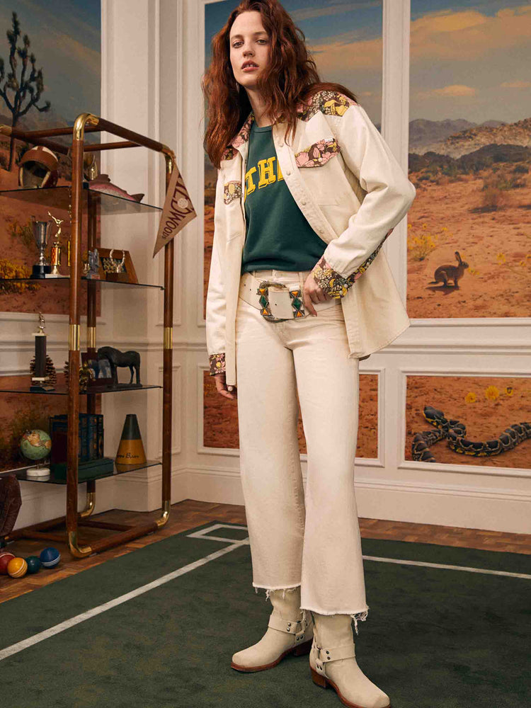 Editorial shot of a woman in a creamy white mid-rise  jeans with a loose fit, wide leg and ankle-length inseam with a frayed hem. 