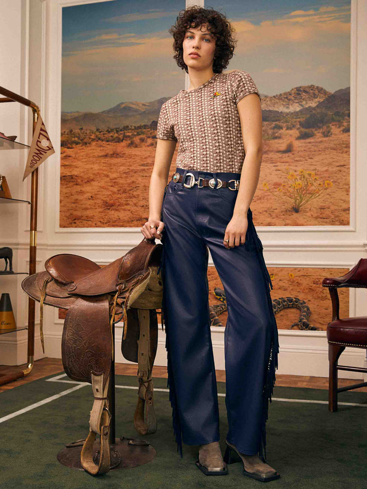 Editorial shot of a woman in cream and brown checkered print with an embroidered cowboy hat tee. 