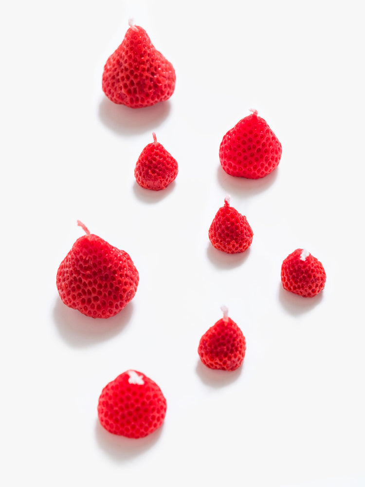 Over view strawberry-shaped candle set made from a blend of soy wax and beeswax in light pink and red in a set of 8.