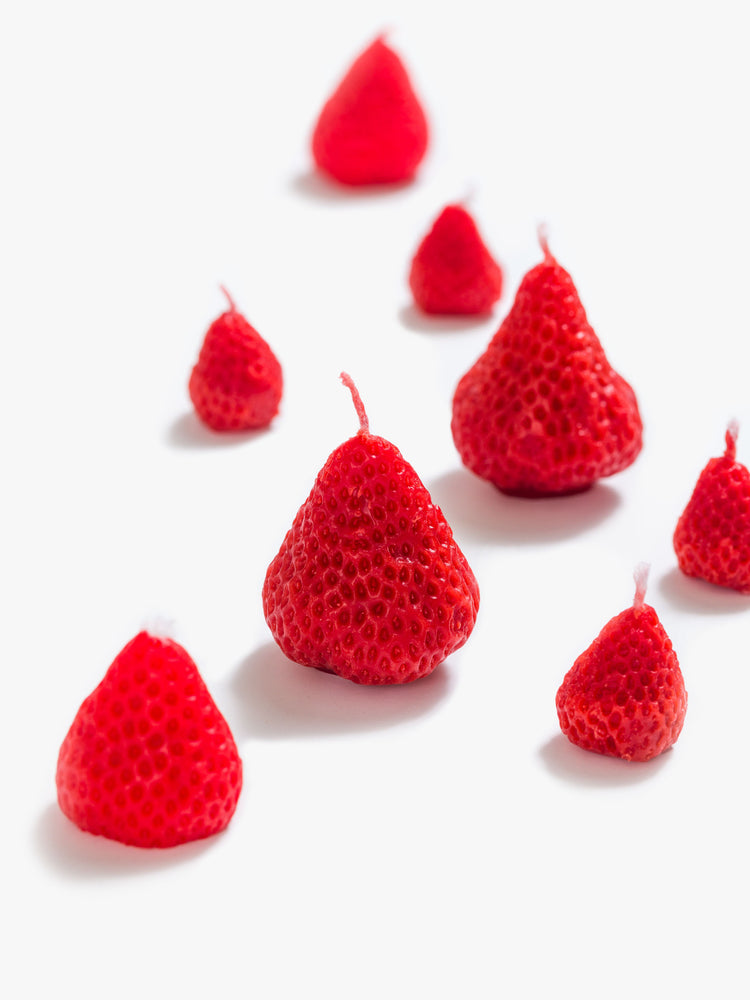 Over view strawberry-shaped candle set made from a blend of soy wax and beeswax in light pink and red in a set of 8.