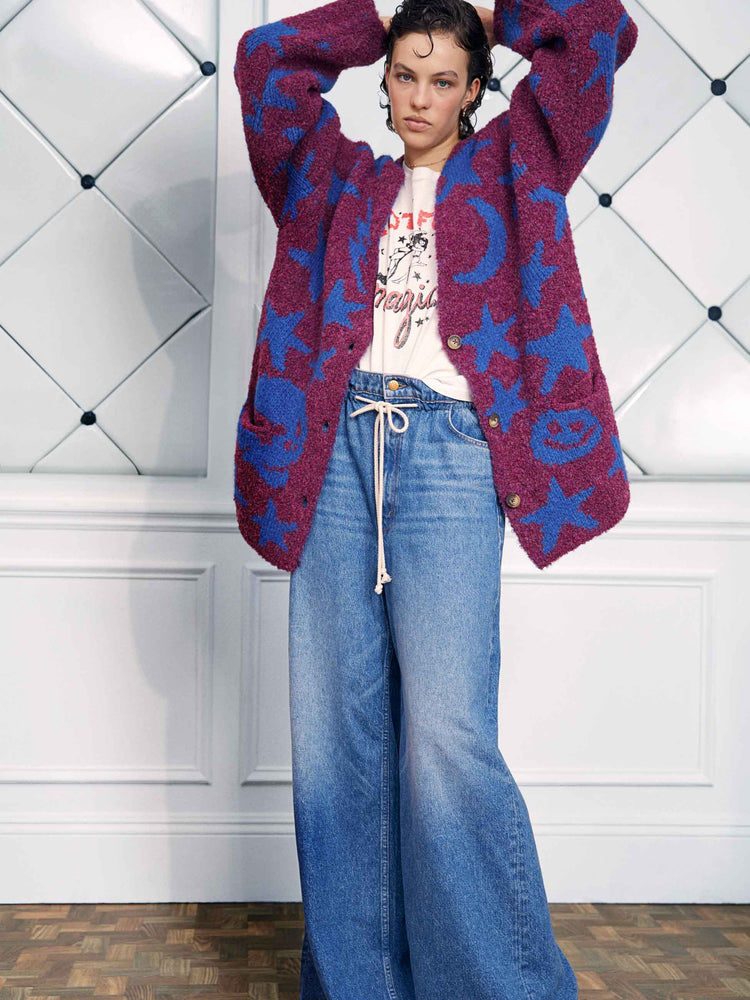 An editorial image of a woman wearing an oversized cardigan with baggy blue jeans.