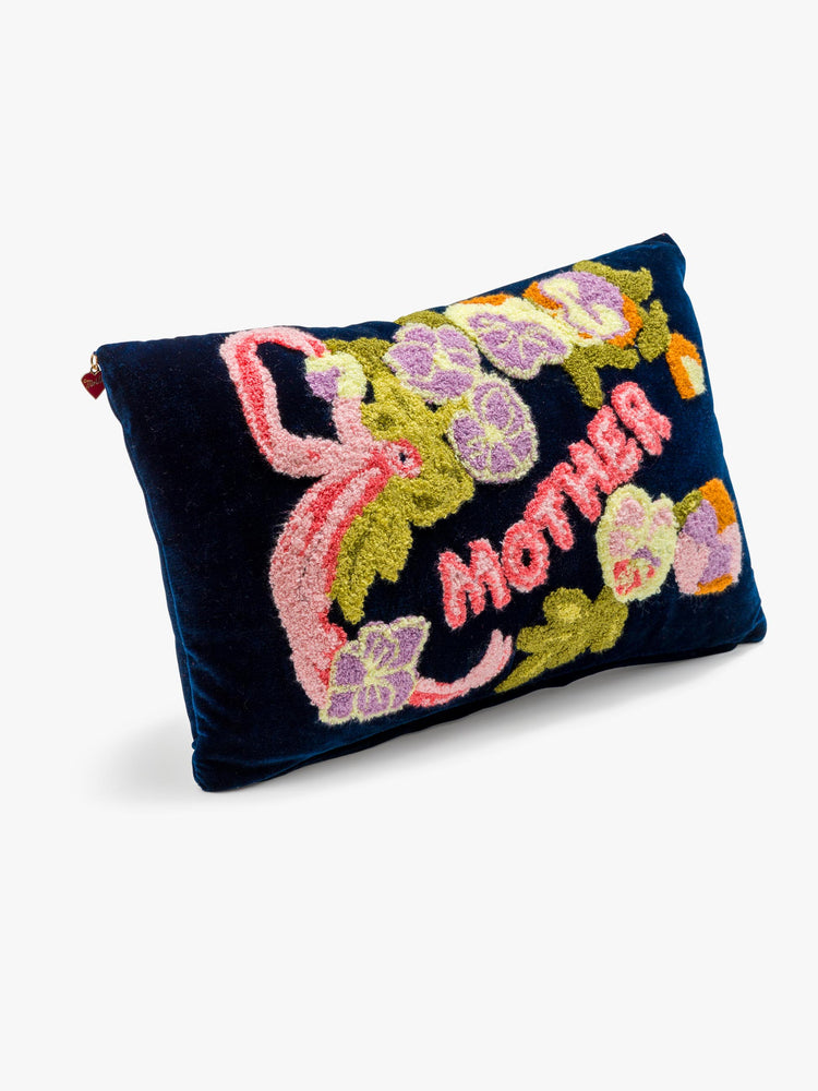 Side angle view of a cozy, navy blue throw pillow with colorful leaves, flowers and MOTHER's name in pink on the front.