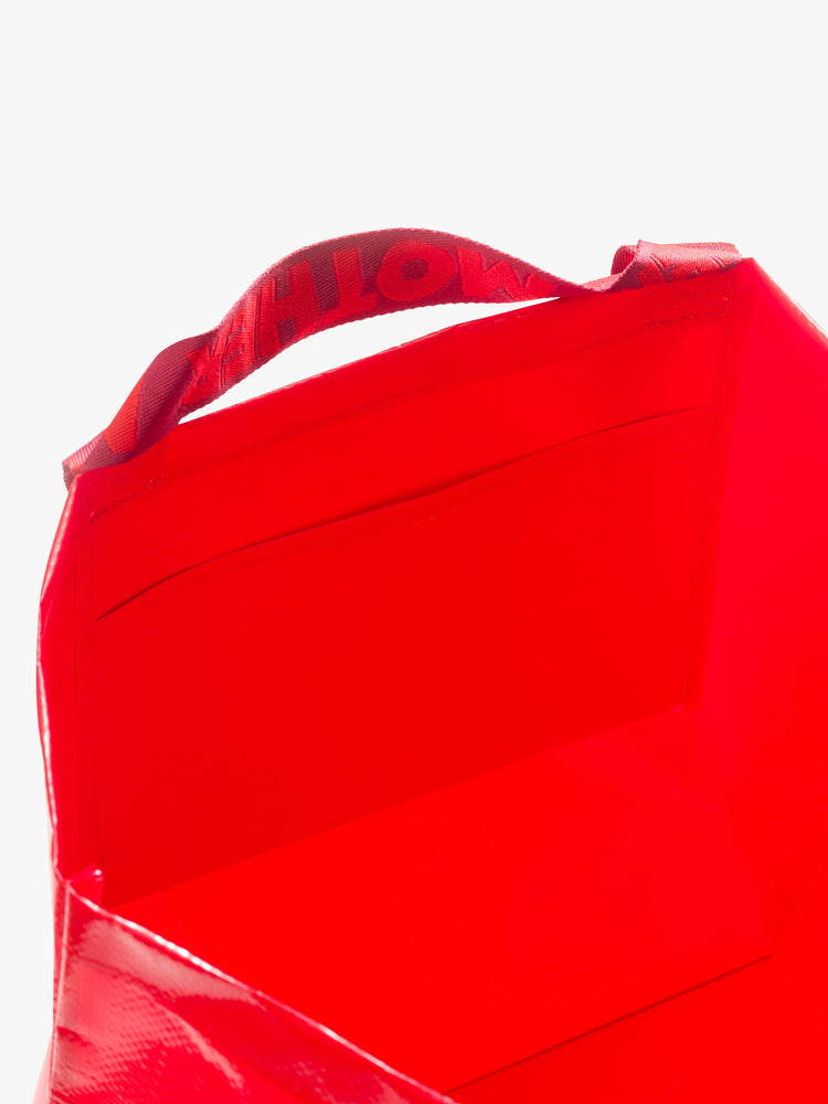 Opening view of a set of two, the red bags feature a boxy, oversized shape, roomy interior, internal pocket, charm, thick branded straps and a pink dust bag.