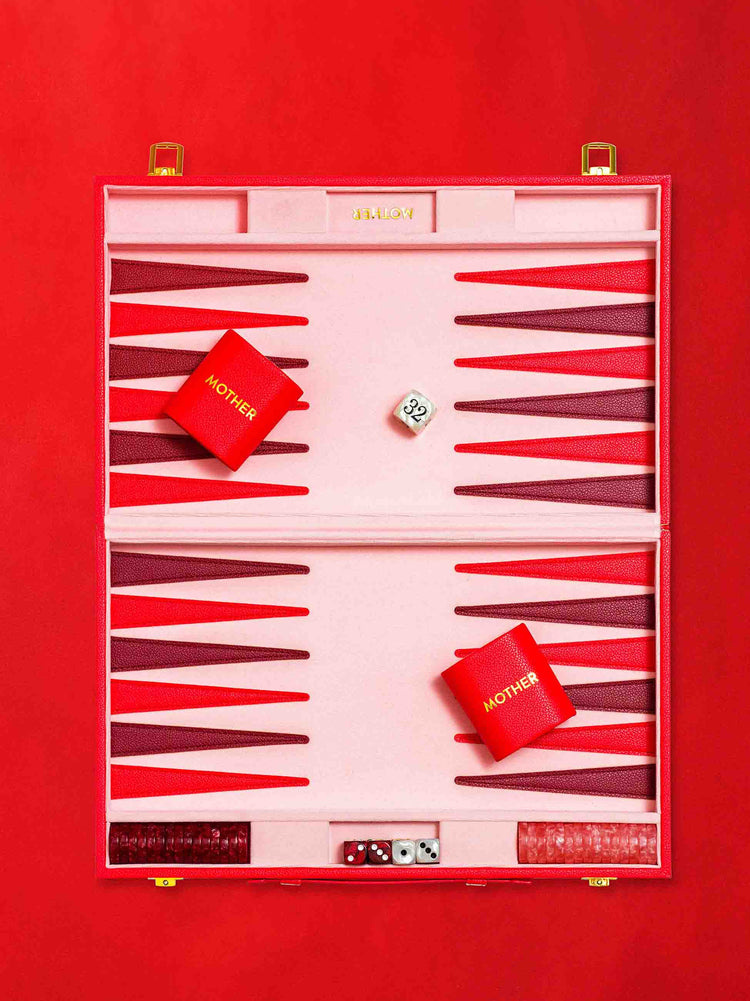 Flat view of a custom backgammon set is designed in pink, red and maroon, against a red background.