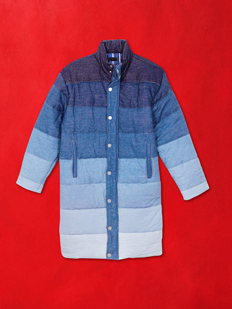 A flat product image of a long puffer jacket in a blue gradient against a red background.