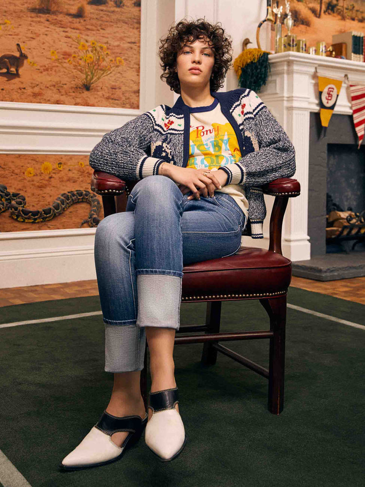 Editorial shot of a woman in a mid blue high-rise straight-leg jeans with an ankle-length inseam and a clean, cuffed hem.