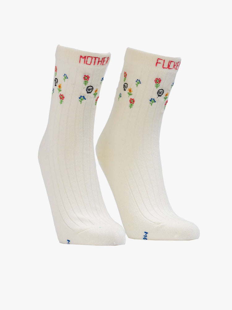 View of classic tube socks in pale yellow with embroidered skulls and flowers.