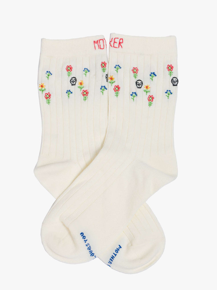 View of classic tube socks in pale yellow with embroidered skulls and flowers.