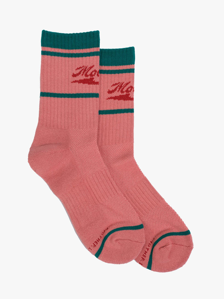 Flat side view of coral pink socks with red lettering and green details.