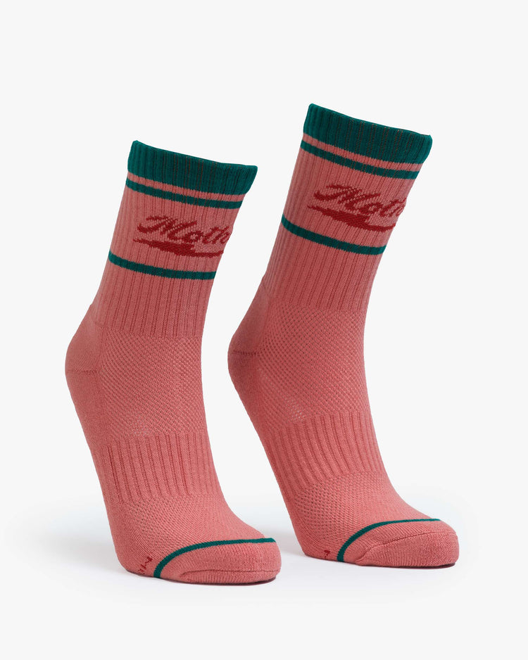 Side view of coral pink socks with red lettering and green details.