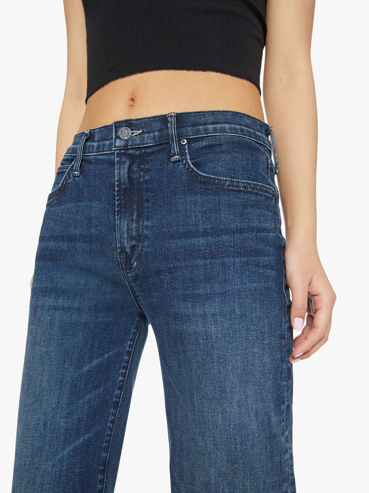 Close up waist view of a petites woman in a dark blue high-rise straight leg jean with a 30-inch inseam and a clean hem.