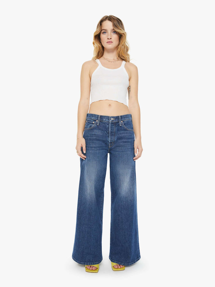 Front view of a petite woman  wide-leg jeans feature a button fly, low-set back pockets, high rise with a slouchy fit and a long inseam in a dark blue wash.