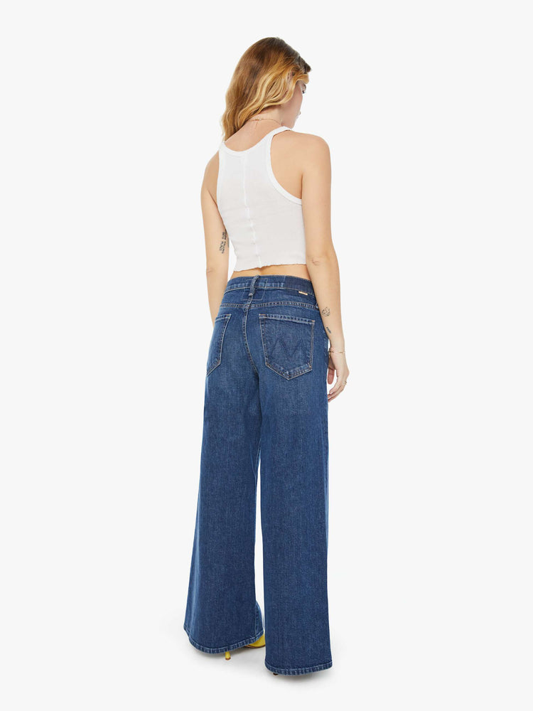 Back view of a petite woman wide-leg jeans feature a button fly, low-set back pockets, high rise with a slouchy fit and a long inseam in a dark blue wash.