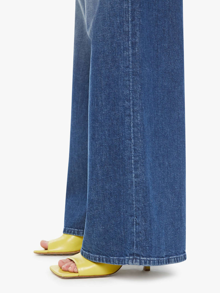 Hem view of a petite  woman wide-leg jeans feature a button fly, low-set back pockets, high rise with a slouchy fit and a long inseam in a dark blue wash.