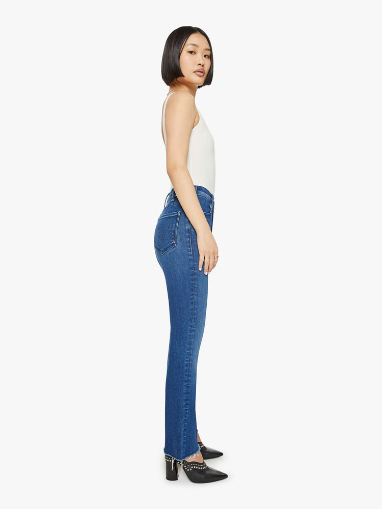 Side  view of a petites high rise bootcut with a 26.5 Inch seam and a frayed hem in a dark blue wash.