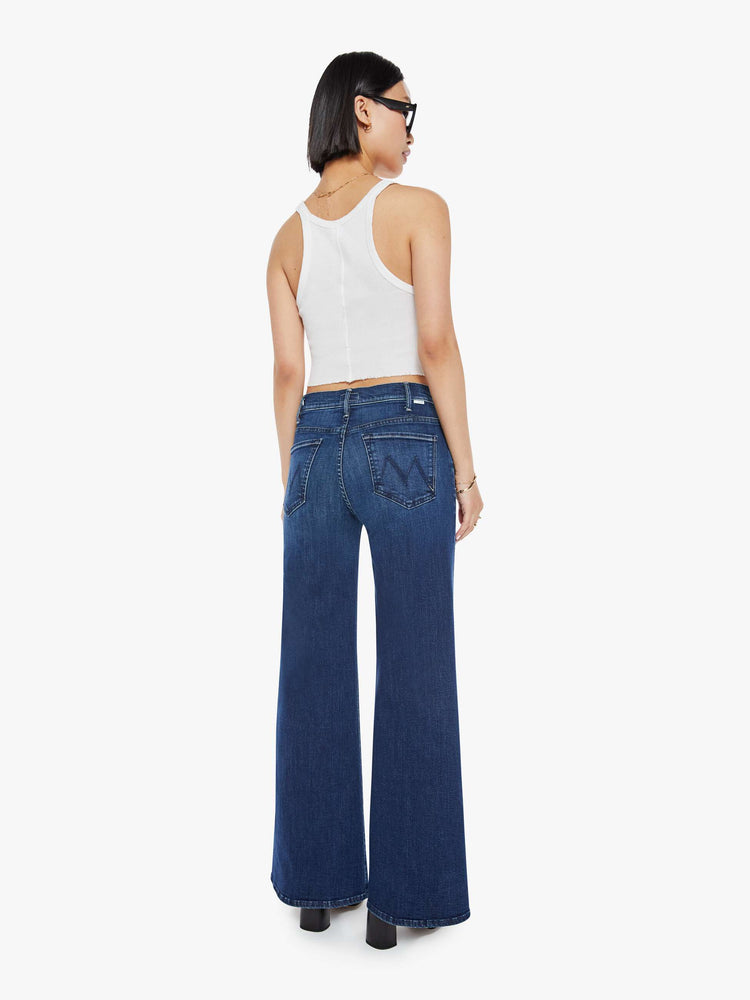 Back view of a petite woman in a dark blue wide leg jeans  with a high rise, 30-inch inseam and a clean hem.