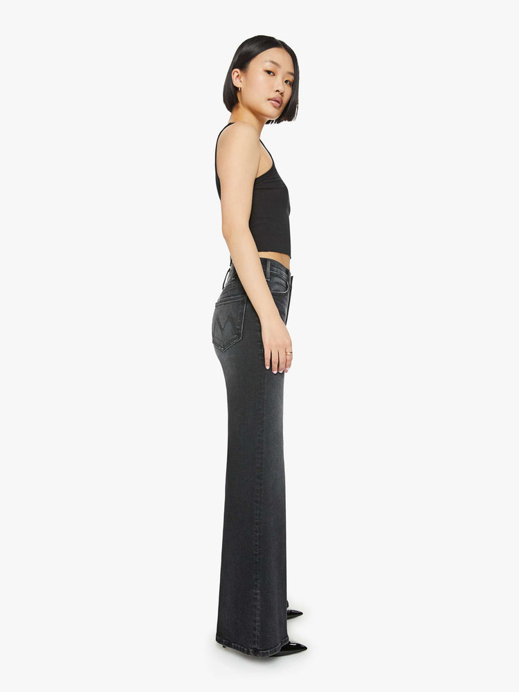 Side view of a petite woman in a black wash  wide leg jeans with a high rise, 30-inch inseam and a clean hem. 