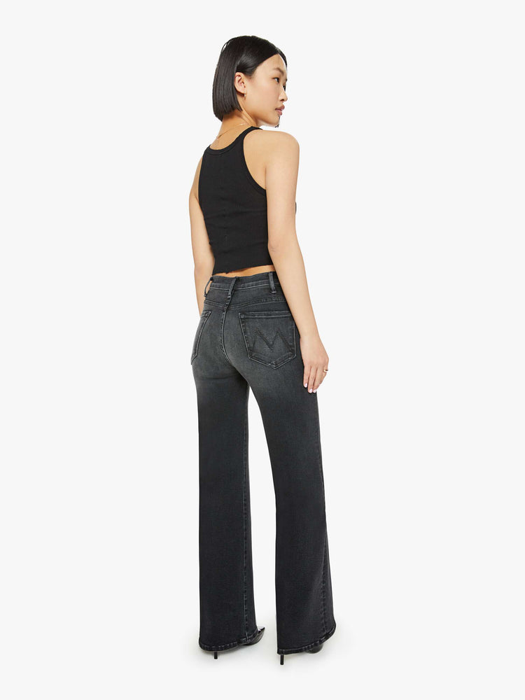 Back view of a petite woman in a black wash  wide leg jeans with a high rise, 30-inch inseam and a clean hem. 