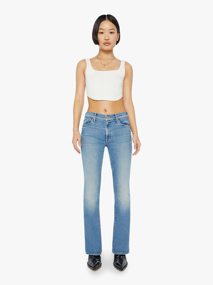 Front view of a petite woman in a light blue mid rise flare jean.