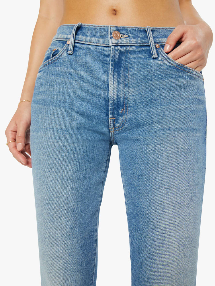 Close up view of a petite woman in a light blue mid rise flare jean.