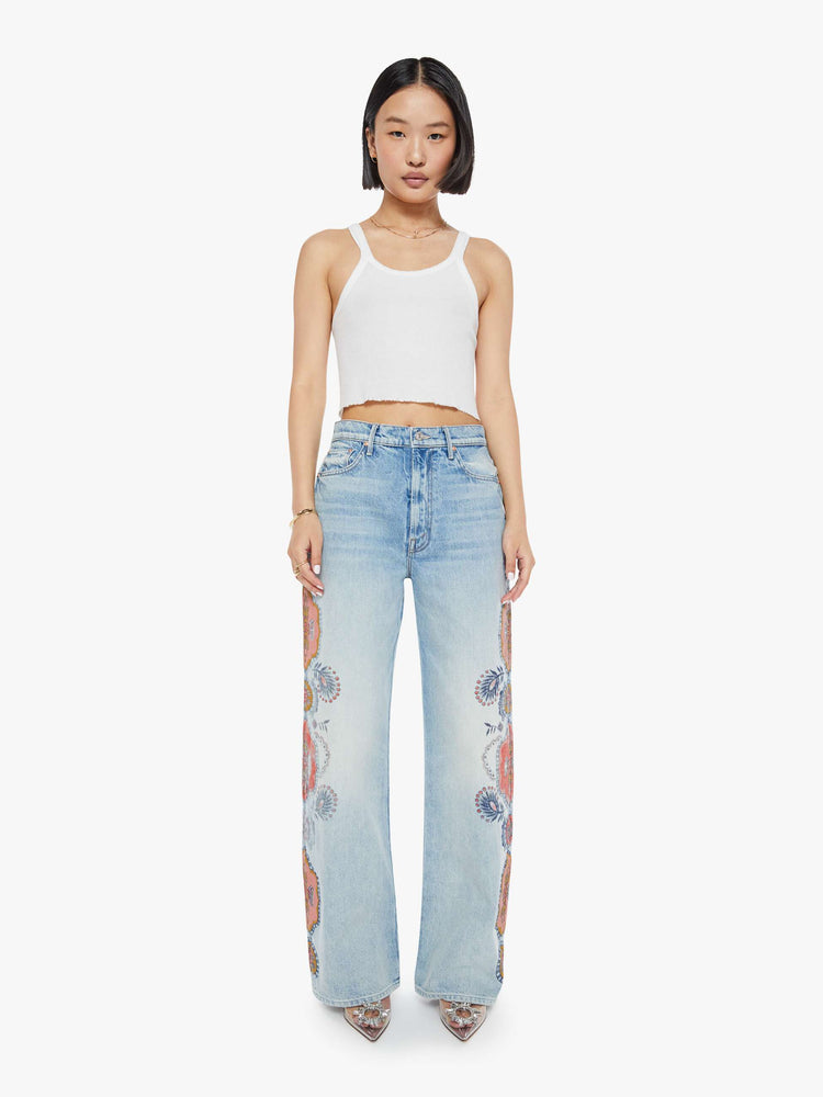 Front view of a high rise wide leg jean in a light blue wash with printed pattern down the side of each leg.