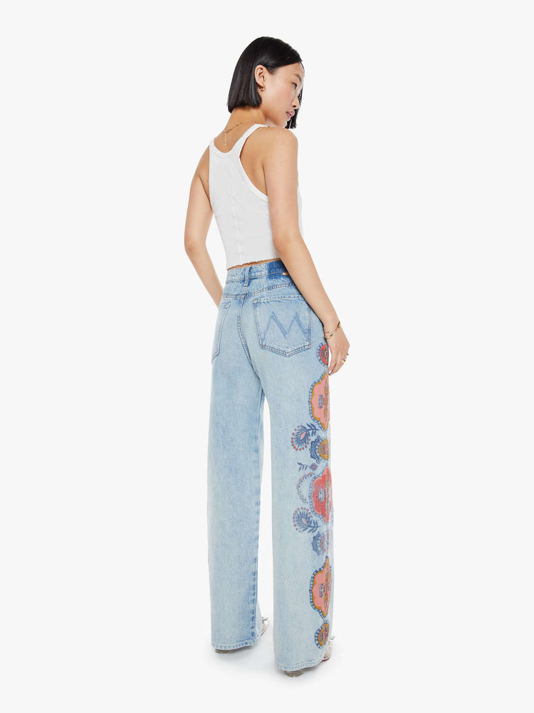 Back view of a high rise wide leg jean in a light blue wash with printed pattern down the side of each leg.