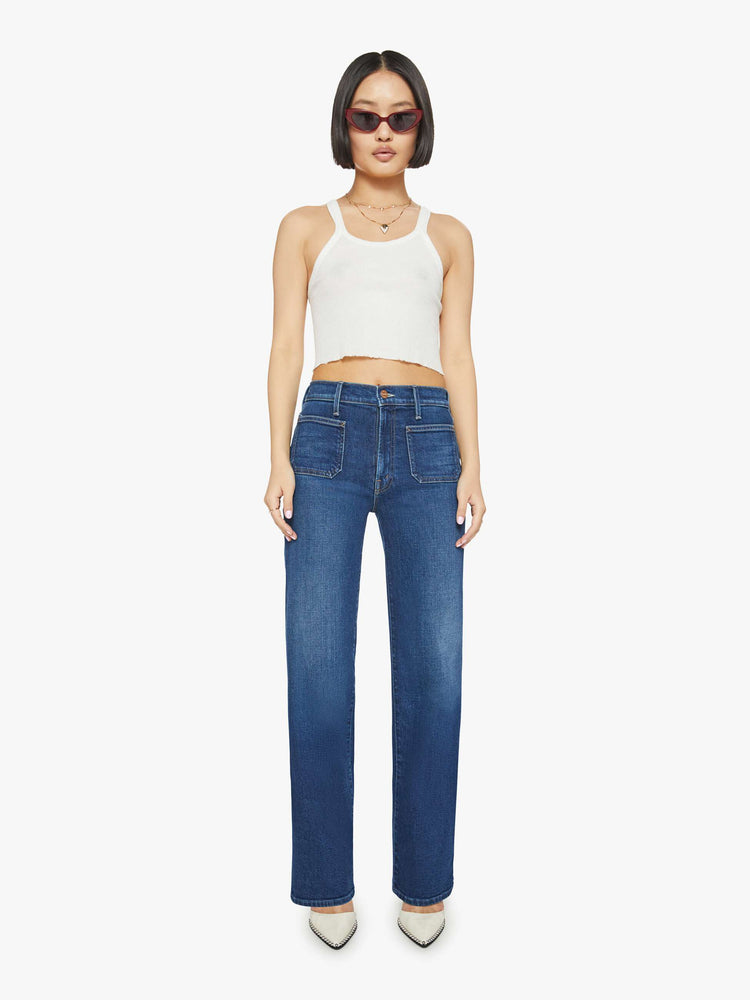 Front view of a petite woman in a dark blue high-waisted jeans with a wide straight leg, zip fly, patch pockets and a long 30-inch inseam with a clean hem. 