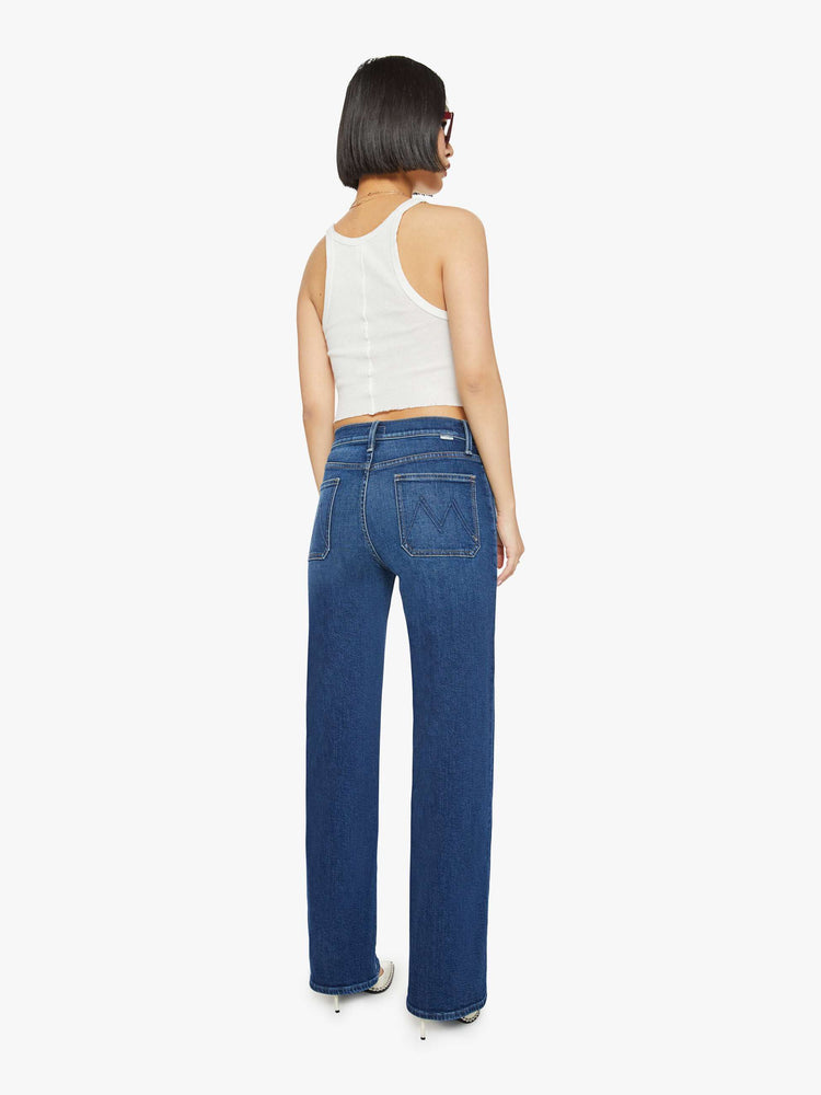 Back view of a petite woman in a dark blue high-waisted jeans with a wide straight leg, zip fly, patch pockets and a long 30-inch inseam with a clean hem. 