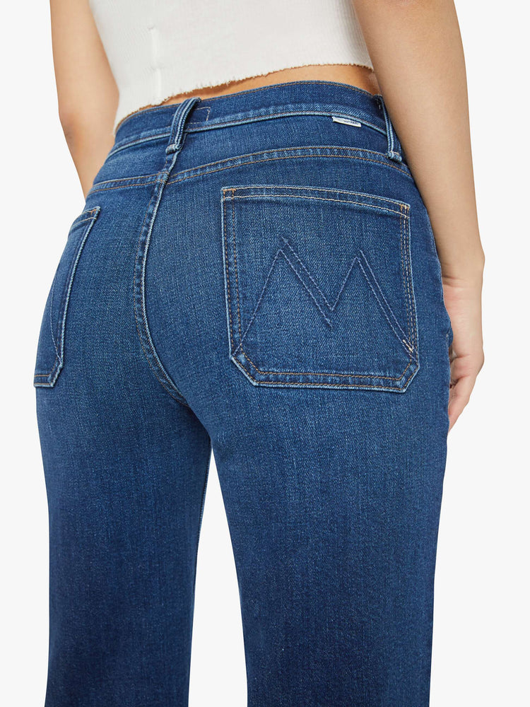 Waist close up view of a petite woman in a dark blue high-waisted jeans with a wide straight leg, zip fly, patch pockets and a long 30-inch inseam with a clean hem. 