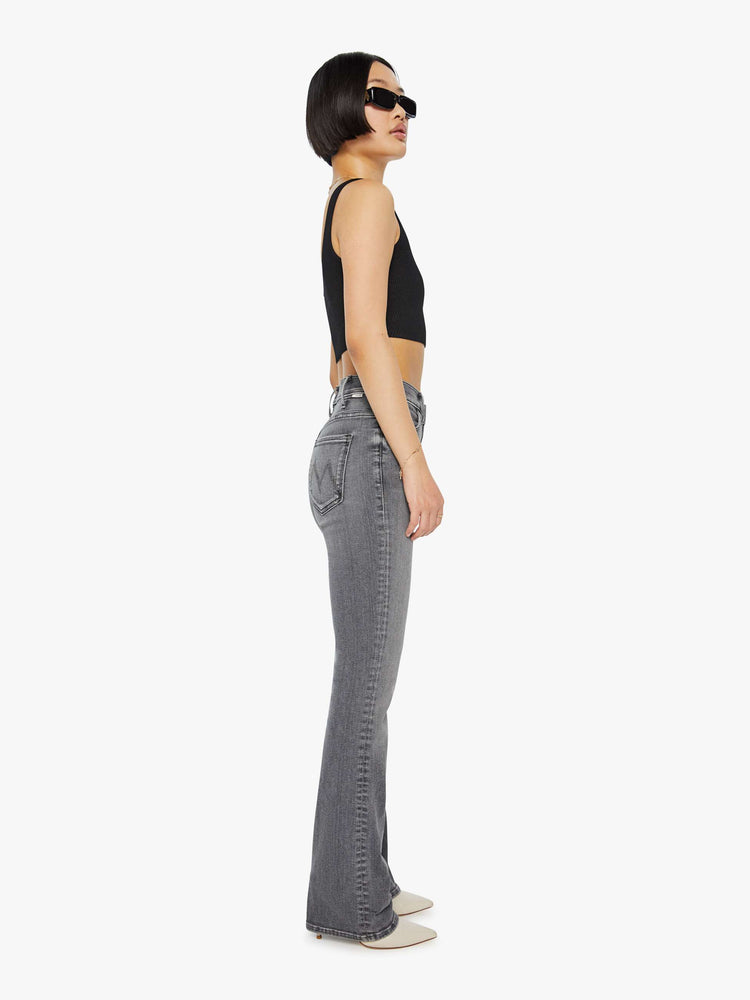 Side view of a woman in a grey High-waisted flare jeans with a longer inseam and a clean hem.