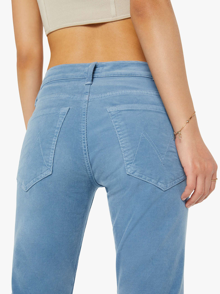 Detailed view of a woman in a light blue corduroy slim straight-leg features a mid rise, button fly, low-set back pockets and a clean hem. 