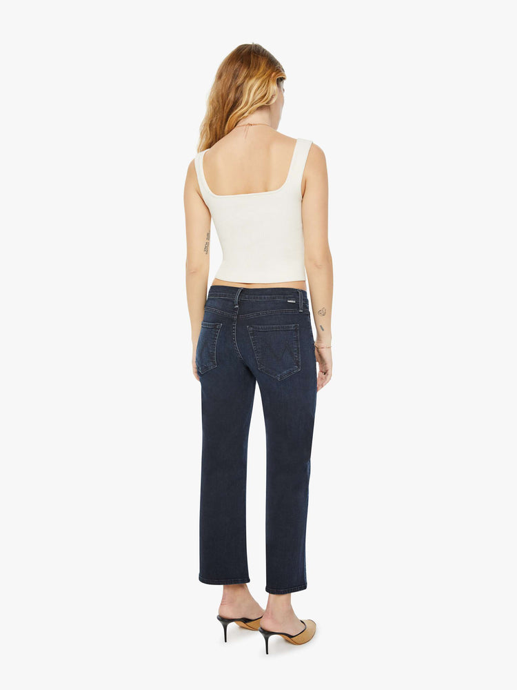 Back view of a petite woman in a dark denim mid-rise jean with a wide straight leg, zip fly and clean ankle-length inseam.