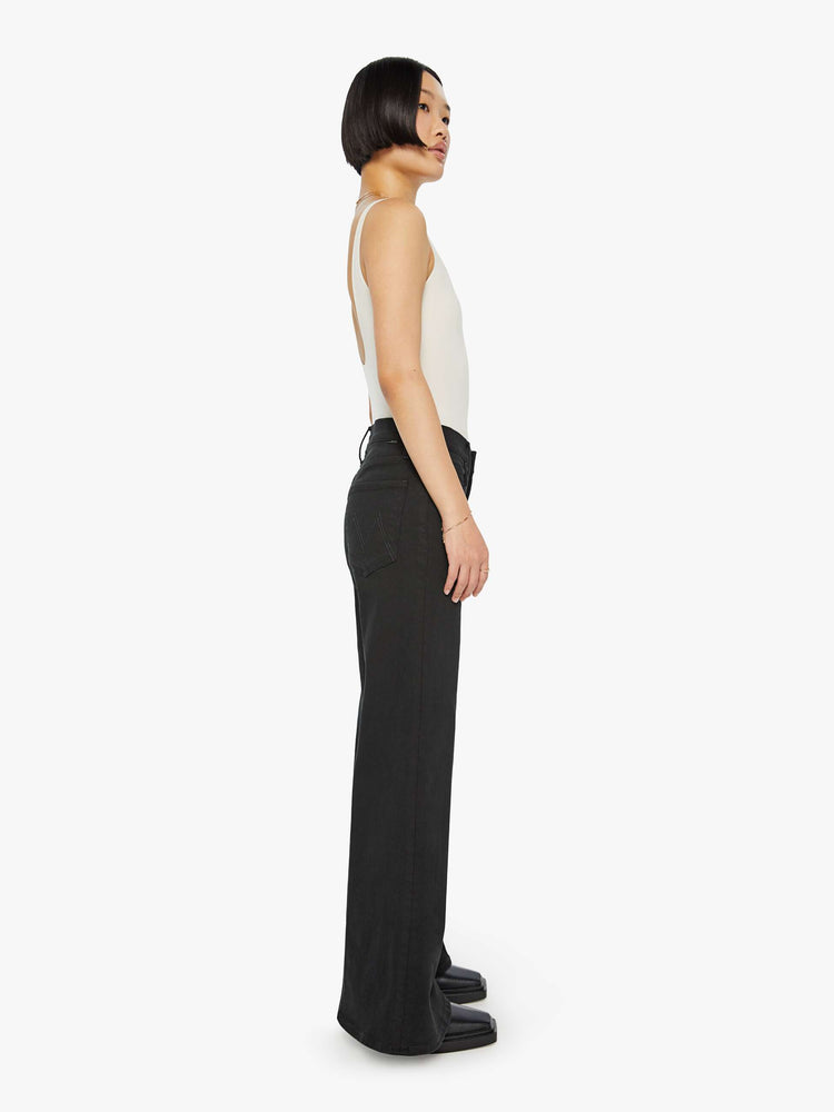 Side view of a woman in a black wide-leg jean with a high rise and a clean, 30-inch inseam.