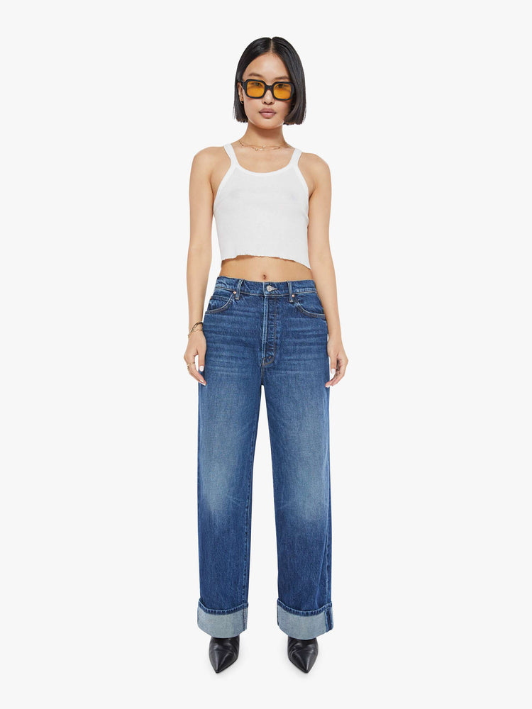 Front view of a woman in dark blue straight-leg jeans have a 28-inch inseam and a cuffed hem.