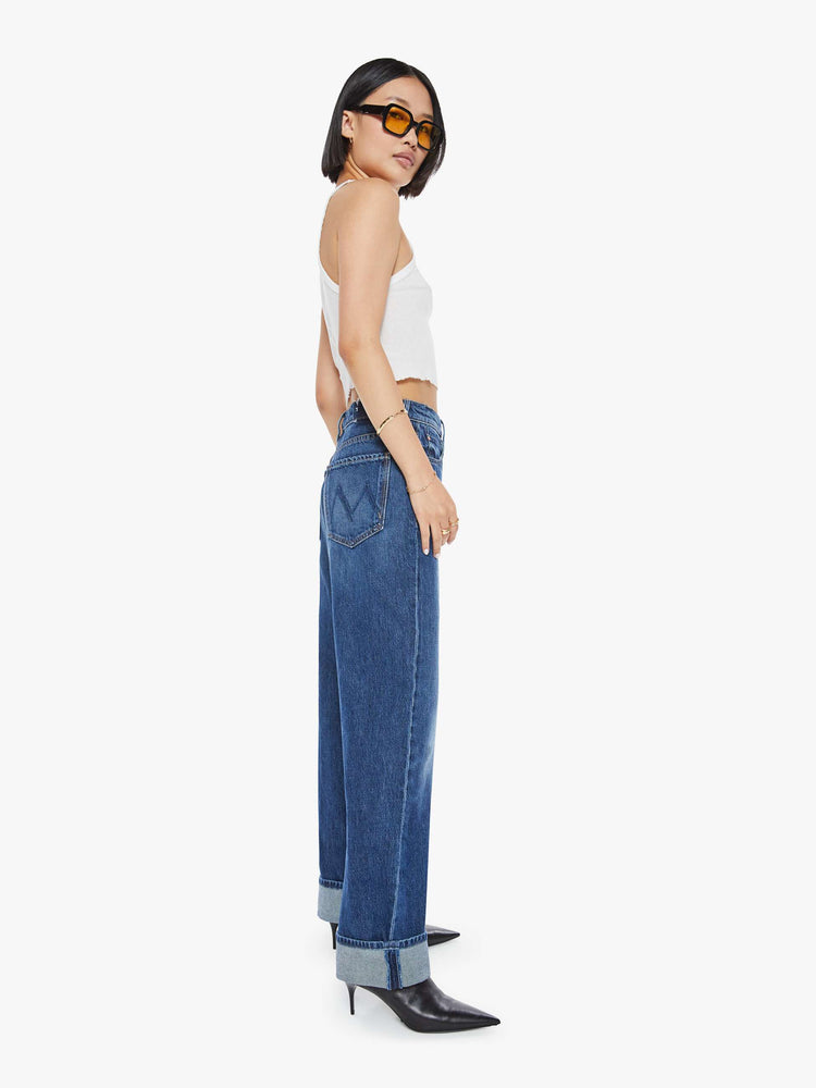 Side view of a woman in dark blue straight-leg jeans have a 28-inch inseam and a cuffed hem.