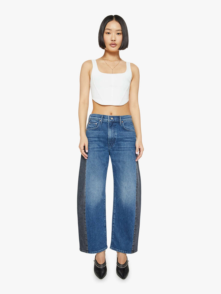 Front view of a petites woman in a black and blue super high-waisted jean with a wide, curved leg, a 26.25-inch inseam and a clean hem.