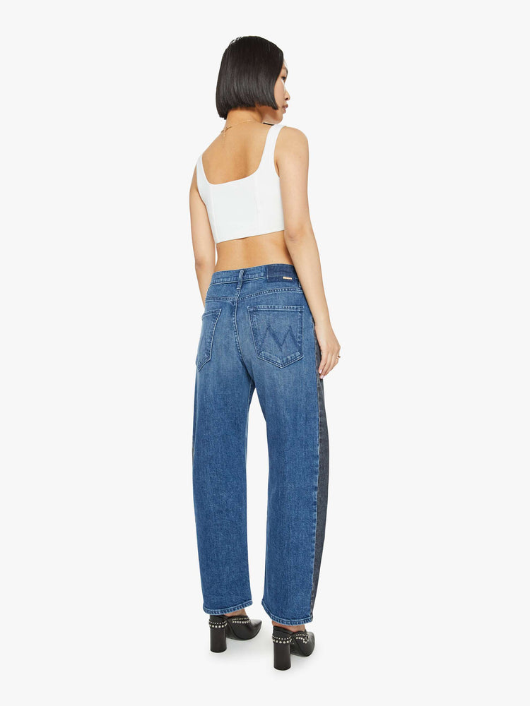 Back view of a petites woman in a black and blue super high-waisted jean with a wide, curved leg, a 26.25-inch inseam and a clean hem.