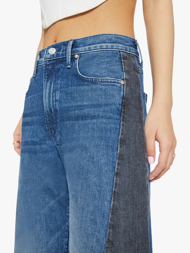 Waist close up view of a petites woman in a black and blue super high-waisted jean with a wide, curved leg, a 26.25-inch inseam and a clean hem.