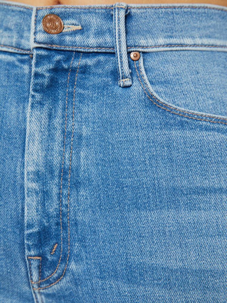 Swatch view of a petite woman in medium blue flare  jean has a high rise with a 29-inch length inseam and a frayed hem. 