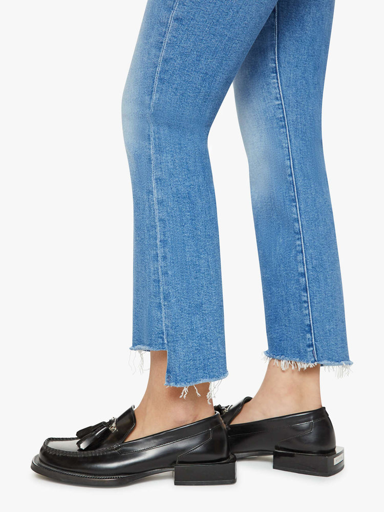 Hem view of a petites woman high-waisted bootcut is cropped at the ankle with a frayed step-hem in a med blue wash.