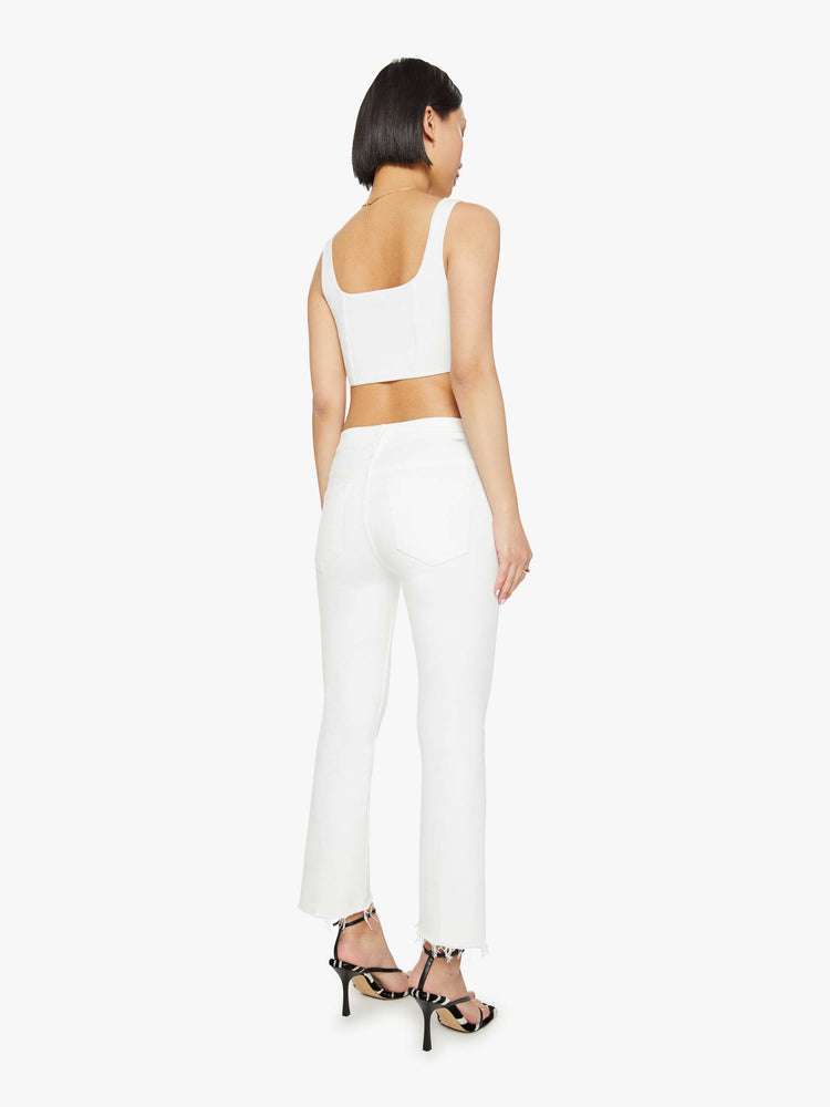 Back view of a petites woman high-waisted bootcut is cropped at the ankle with a frayed step-hem in a white wash.